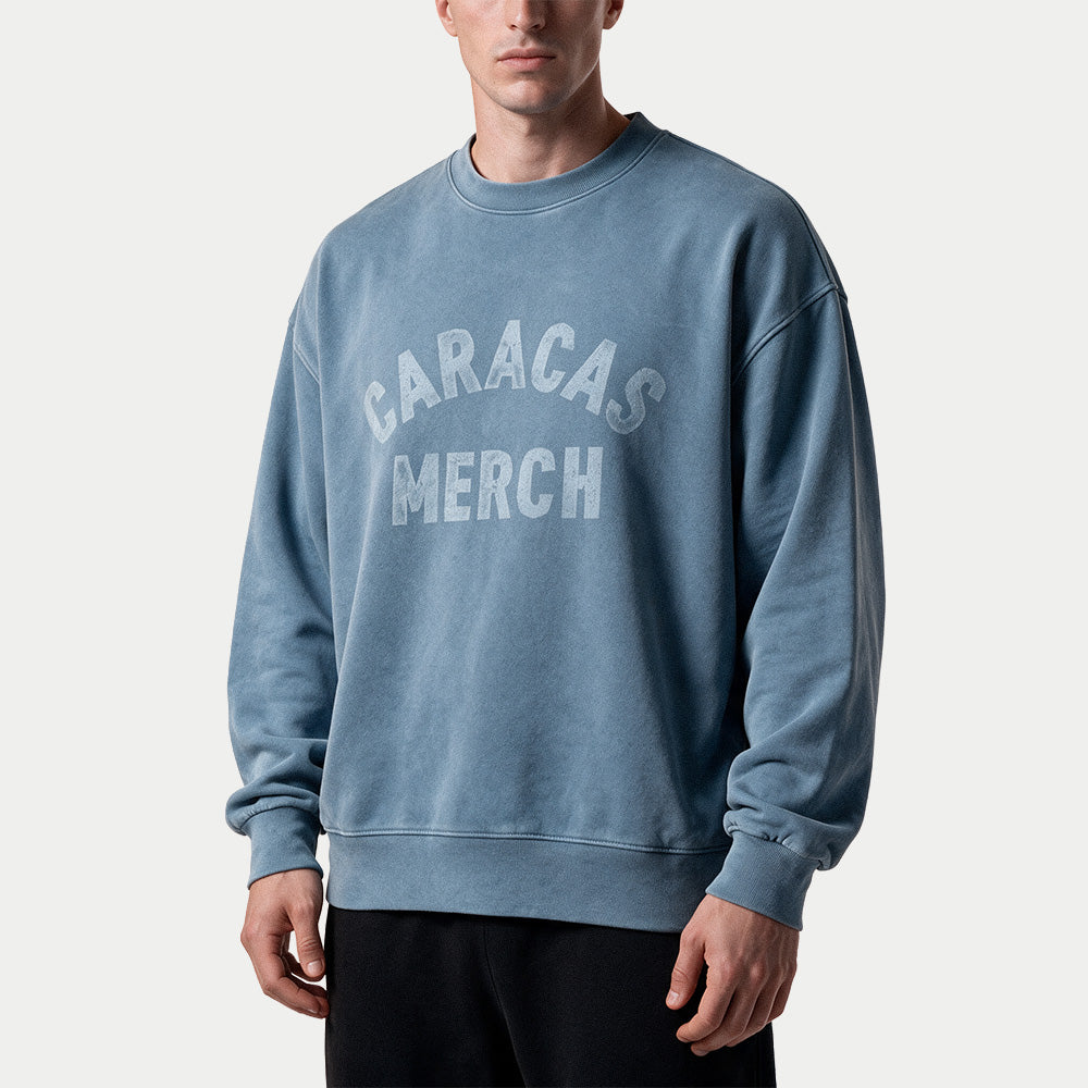 Male model wearing the blue oversized vintage wash crewneck by Caracas Merch, front view
